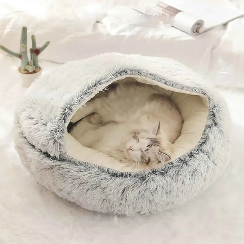 Cat sleeping in a fluffy pet bed on a light surface